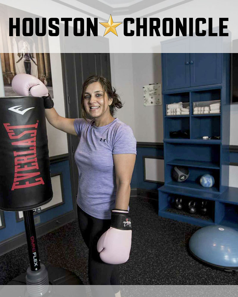 Woman standing next to a punching bag in her exercise room.